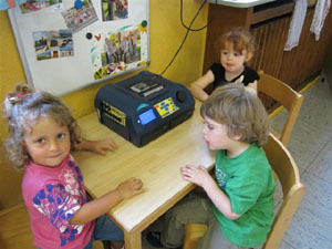 Kinder sitzen am Tisch mit CD-Player.