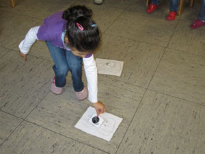 Mädchen legt Lakritzschnecke auf Zettel am Boden.