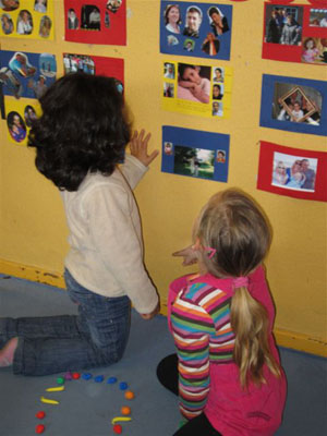 Zwei Kinder zheigen sich die Familienfotos an  der Wand.