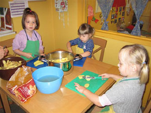 Kinder schneiden Kartoffeln am Küchentisch.