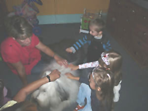 Erzieherin und Kinder streicheln Hund Holly.