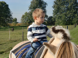 Junge sitzt auf Pony.
