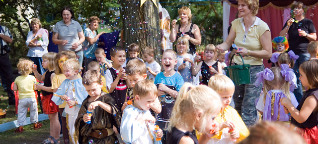 Erzieherinnen und viele Kinder pusten Seifenblasen