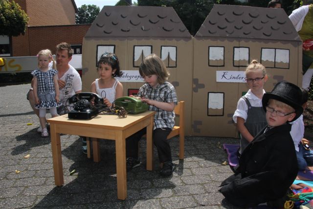 2 Kinder mit alten Telefonen an Tisch
