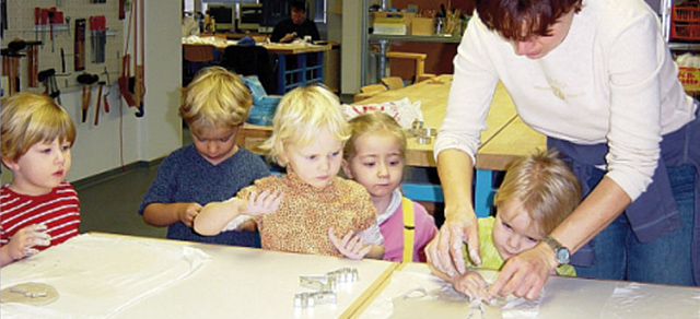 Erzieherin hilft Kindern bei Gipsabdrücken der Hand
