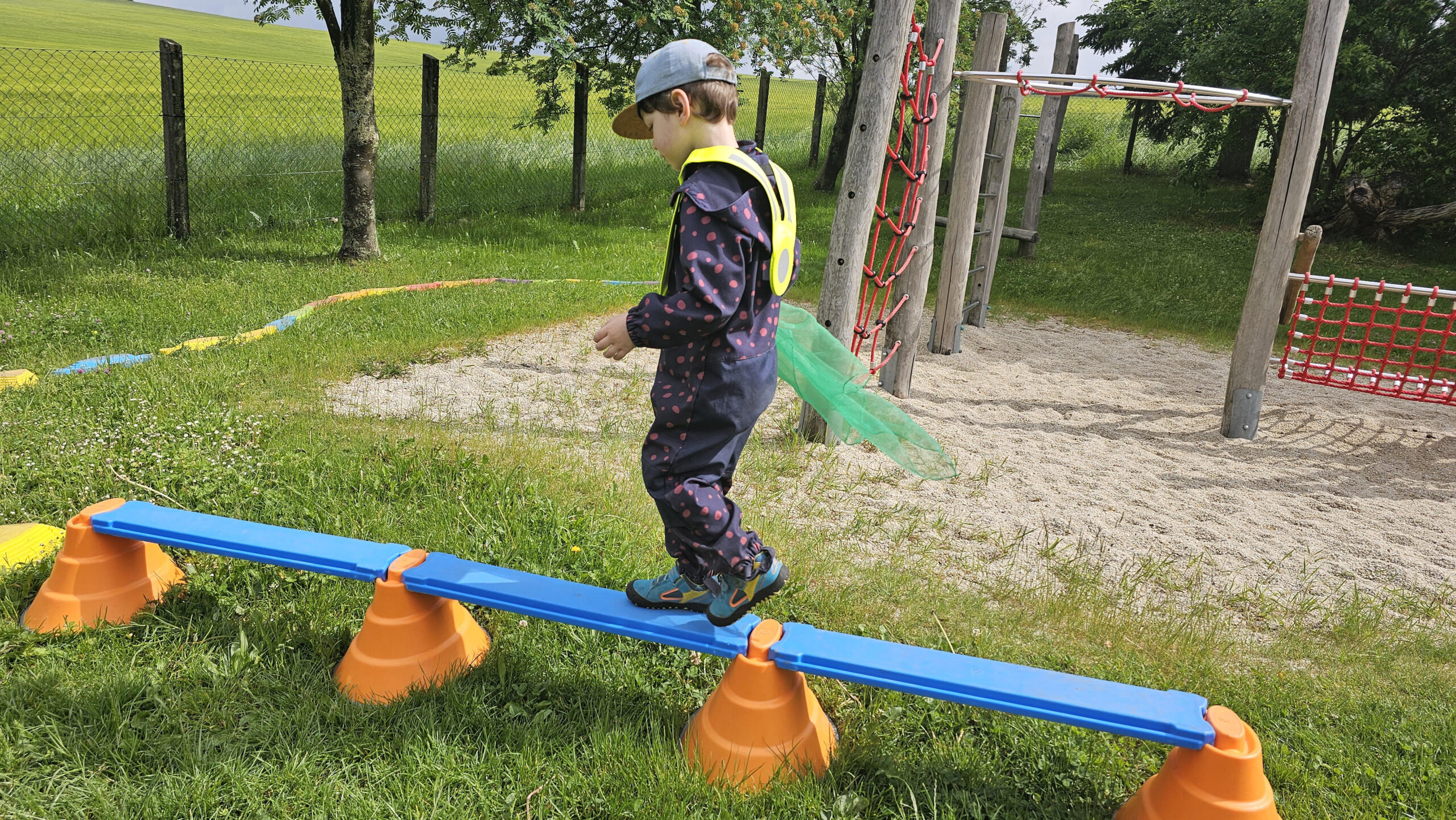 Kleiner Junge balanciert auf Parcours im Garten
