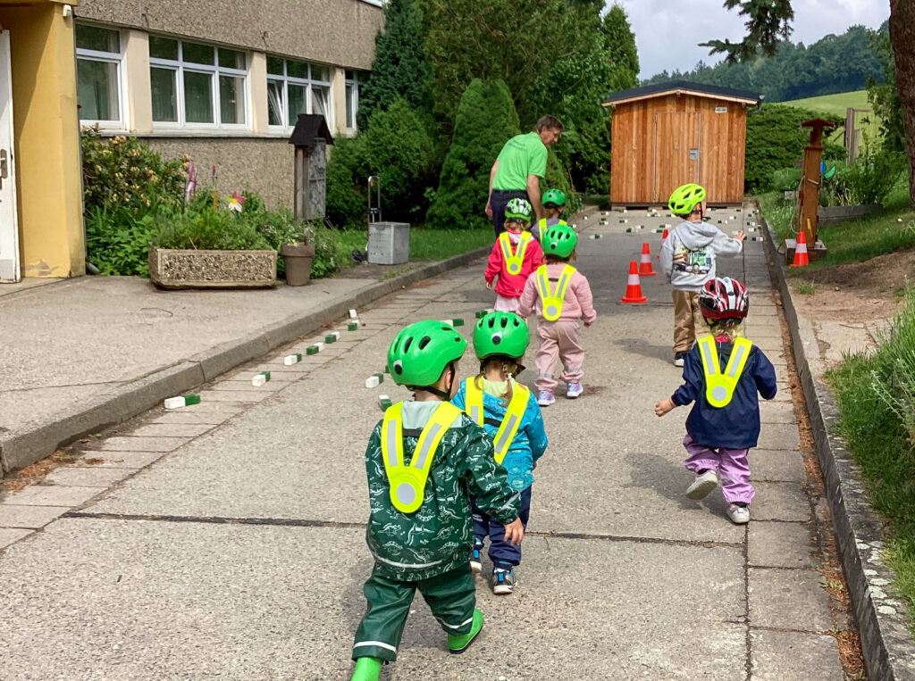 Gruppe kleiner Kinder mit Helmen laufen durch einen Parcours